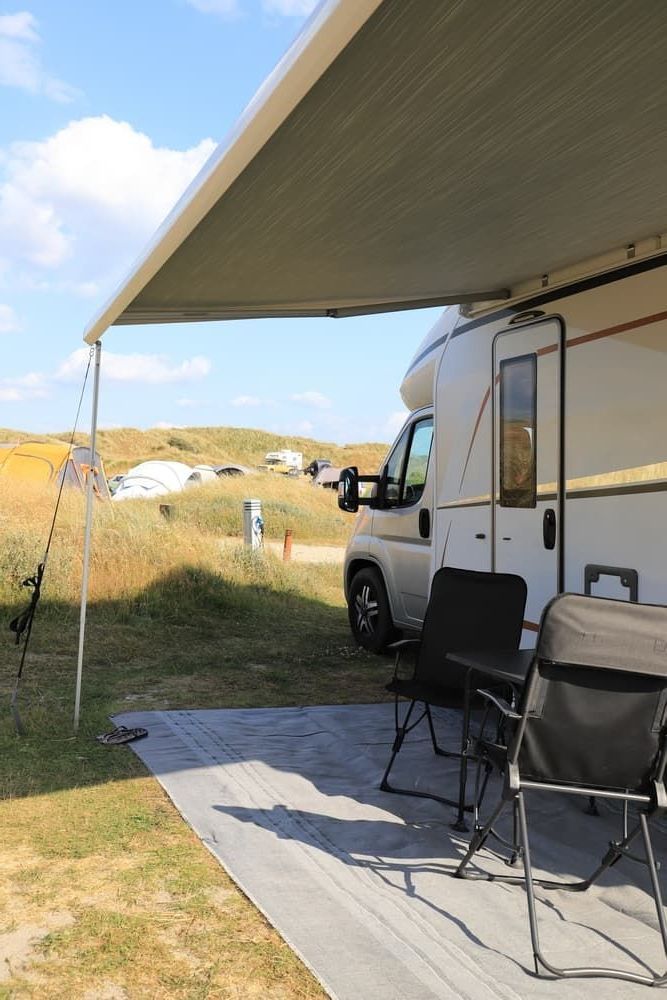 A Camper Van is Parked Under a Canopy in a Field — Lake Macquarie Caravan Repairs In Cardiff, NSW