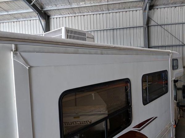 A White RV Is Parked Inside Of A Building — Lake Macquarie Caravan Repairs In Cardiff, NSW