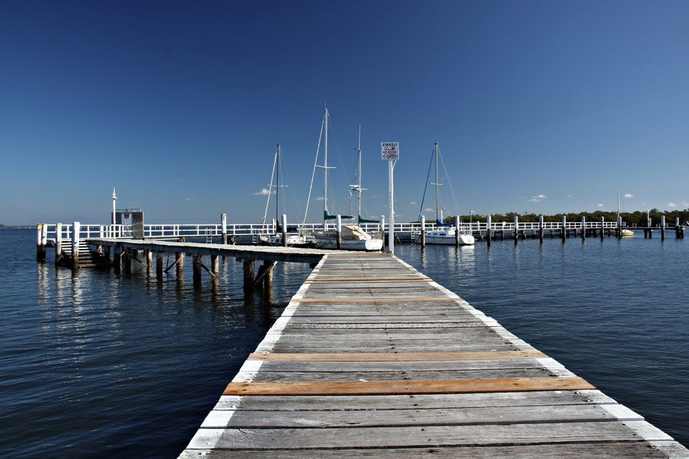 A Wooden Dock Leading Into A Body Of Water — Lake Macquarie Caravan Repairs In Port Stephens, NSW