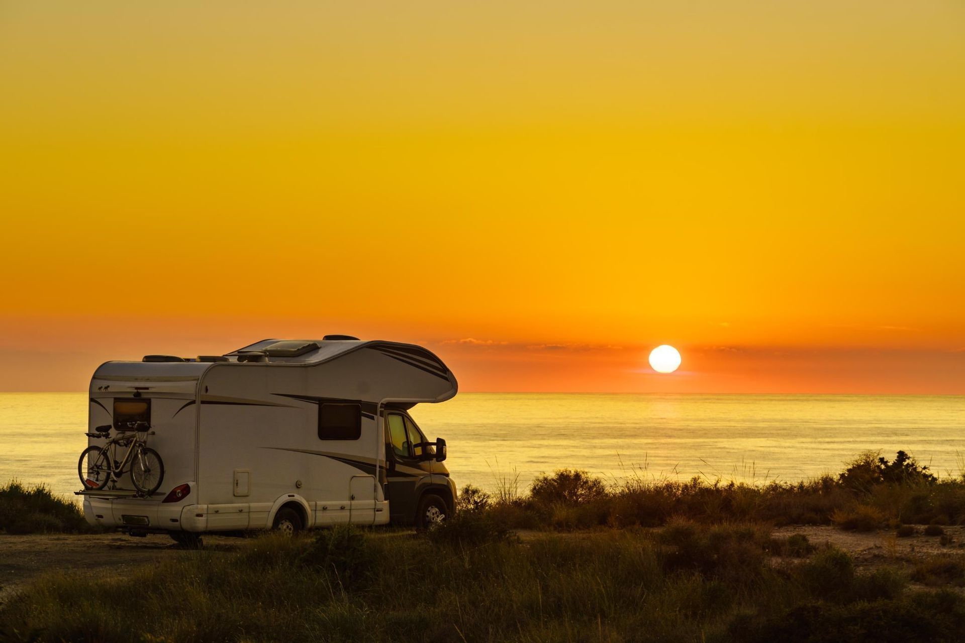 A RV is Parked on the Beach at Sunset — Lake Macquarie Caravan Repairs In Cardiff, NSW