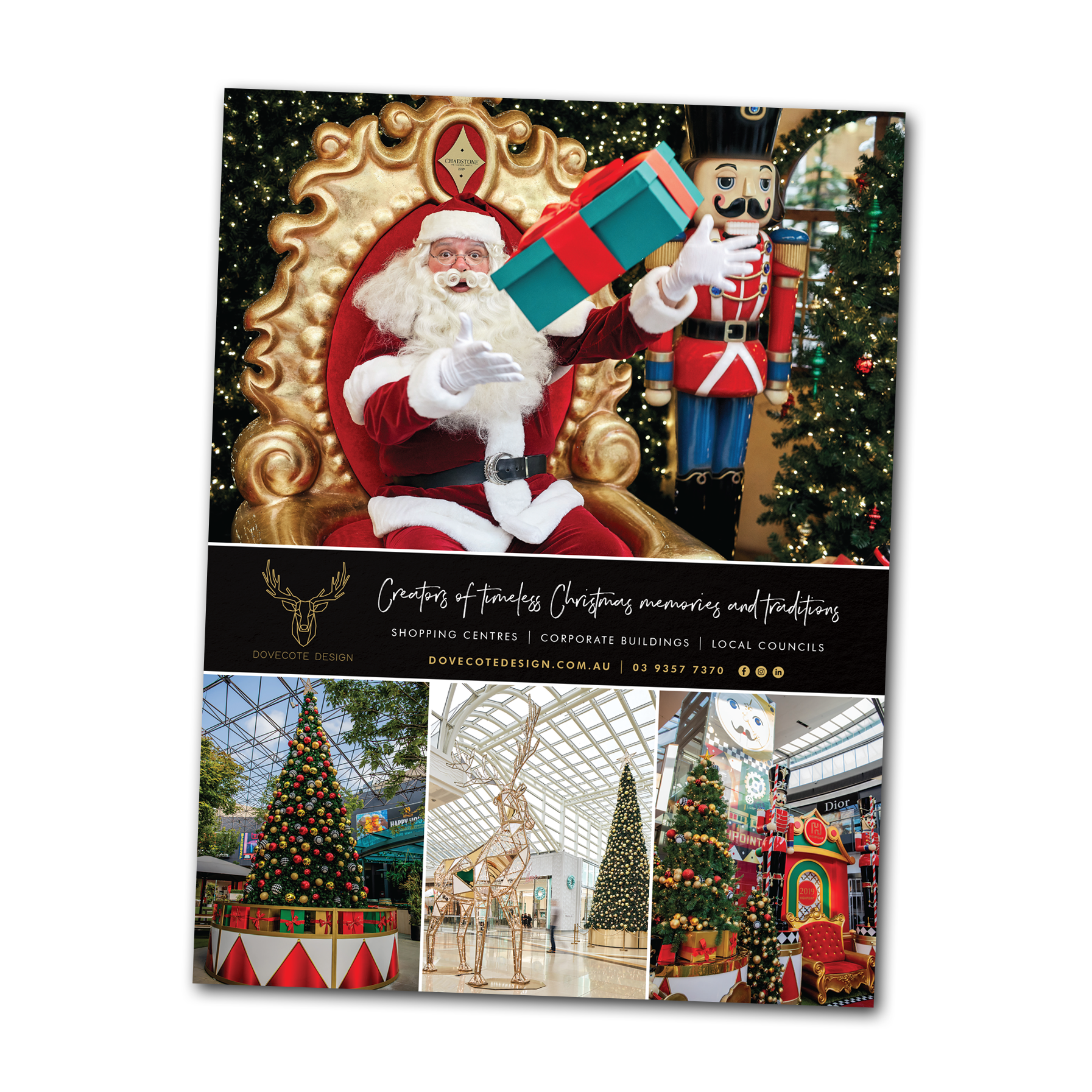 Santa beside a giant gift at a festive Christmas display with decorated trees and holiday scenes
