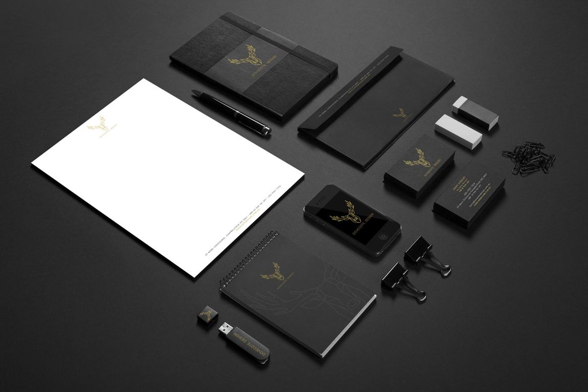 Black and gold corporate branding mock-up on a dark surface: notepad, stationery, business cards, phone.