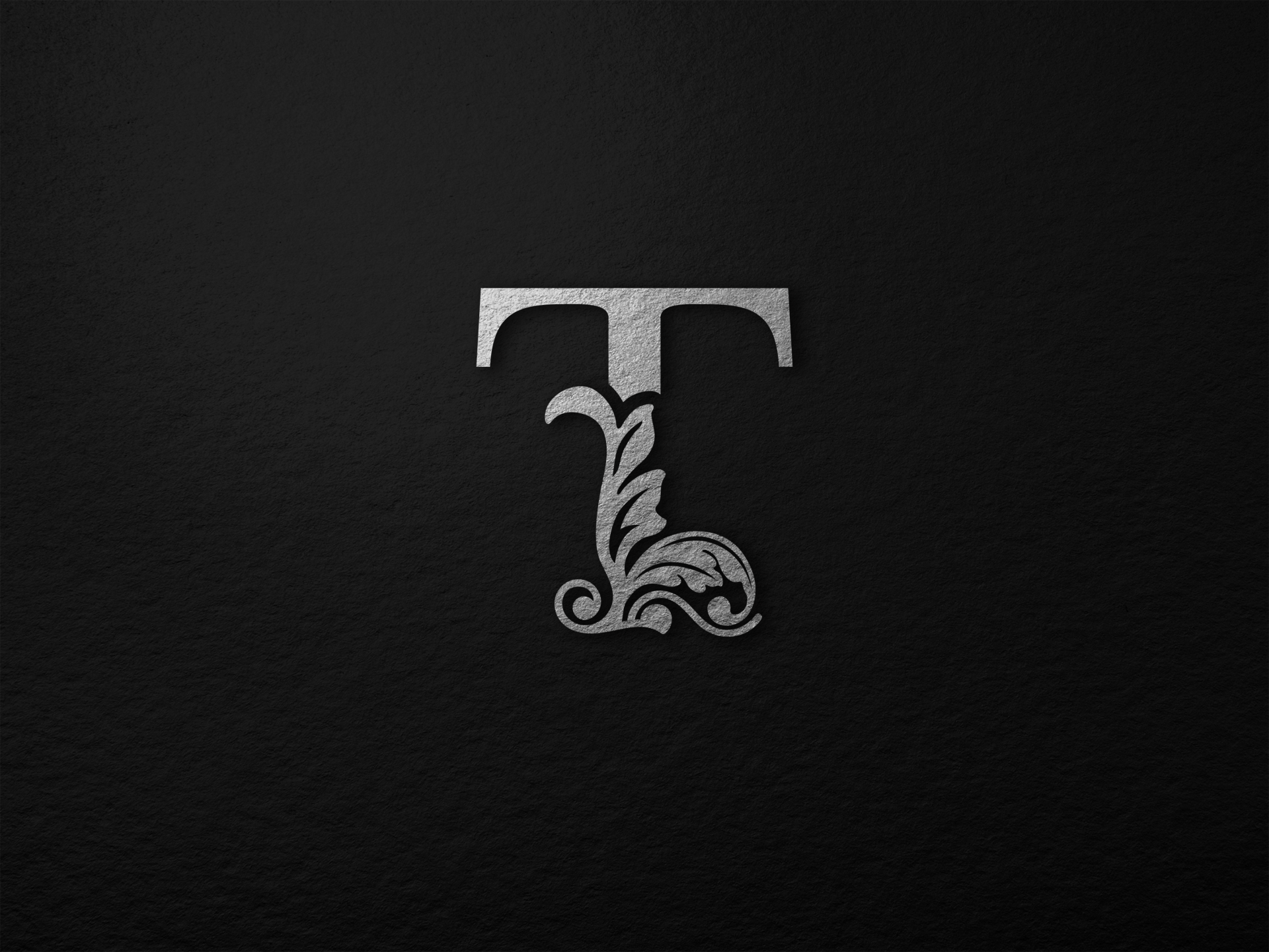 Decorative silver letter T on a dark textured background