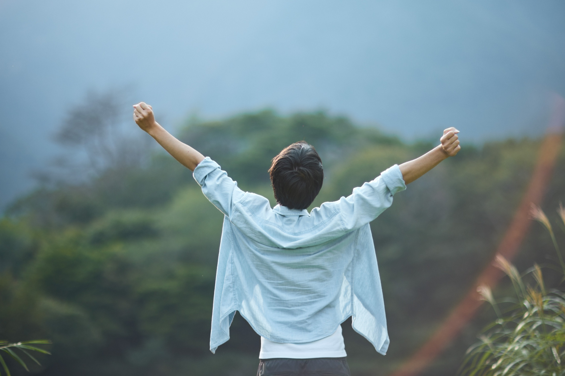 A person stretches joyfully in nature, finally feeling asthma relief. 
