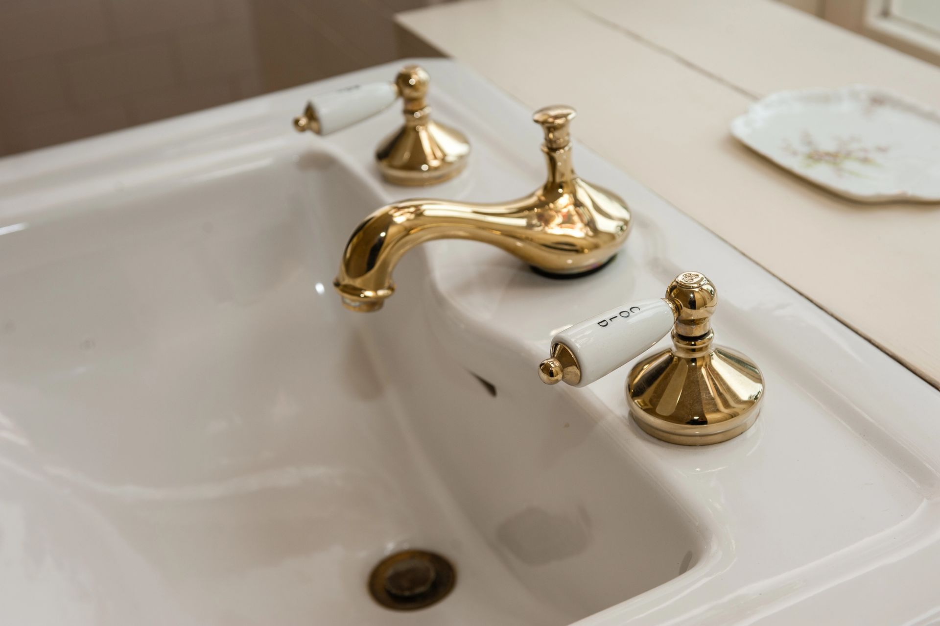 Gold faucet and white sink with gold fixtures in a bathroom setting.