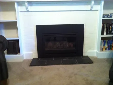a living room with a fireplace built into the wall and bookshelves