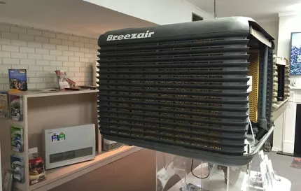 a breezeair air conditioner is hanging from the ceiling in a room .