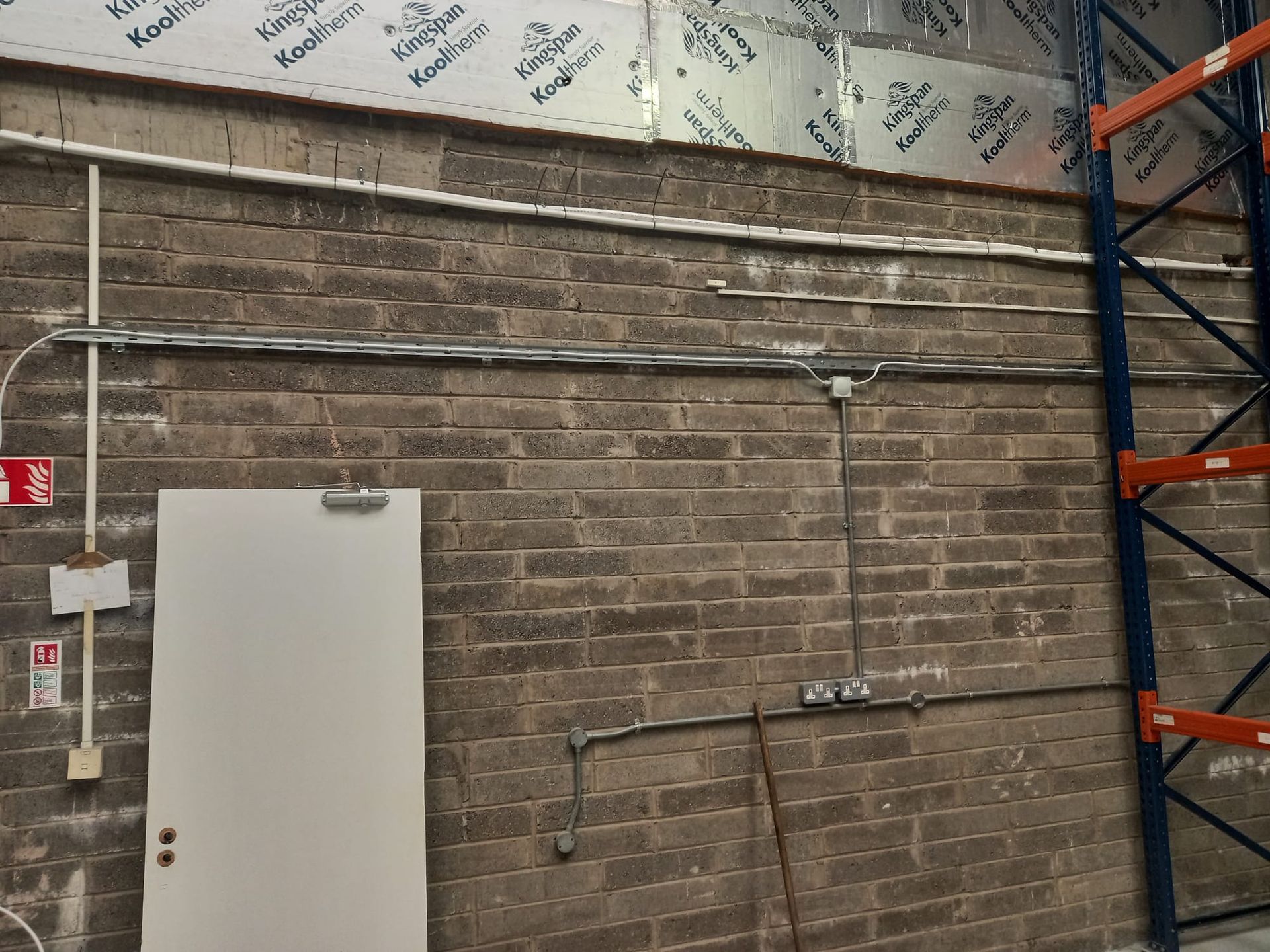 A warehouse with a brick wall and a white door.