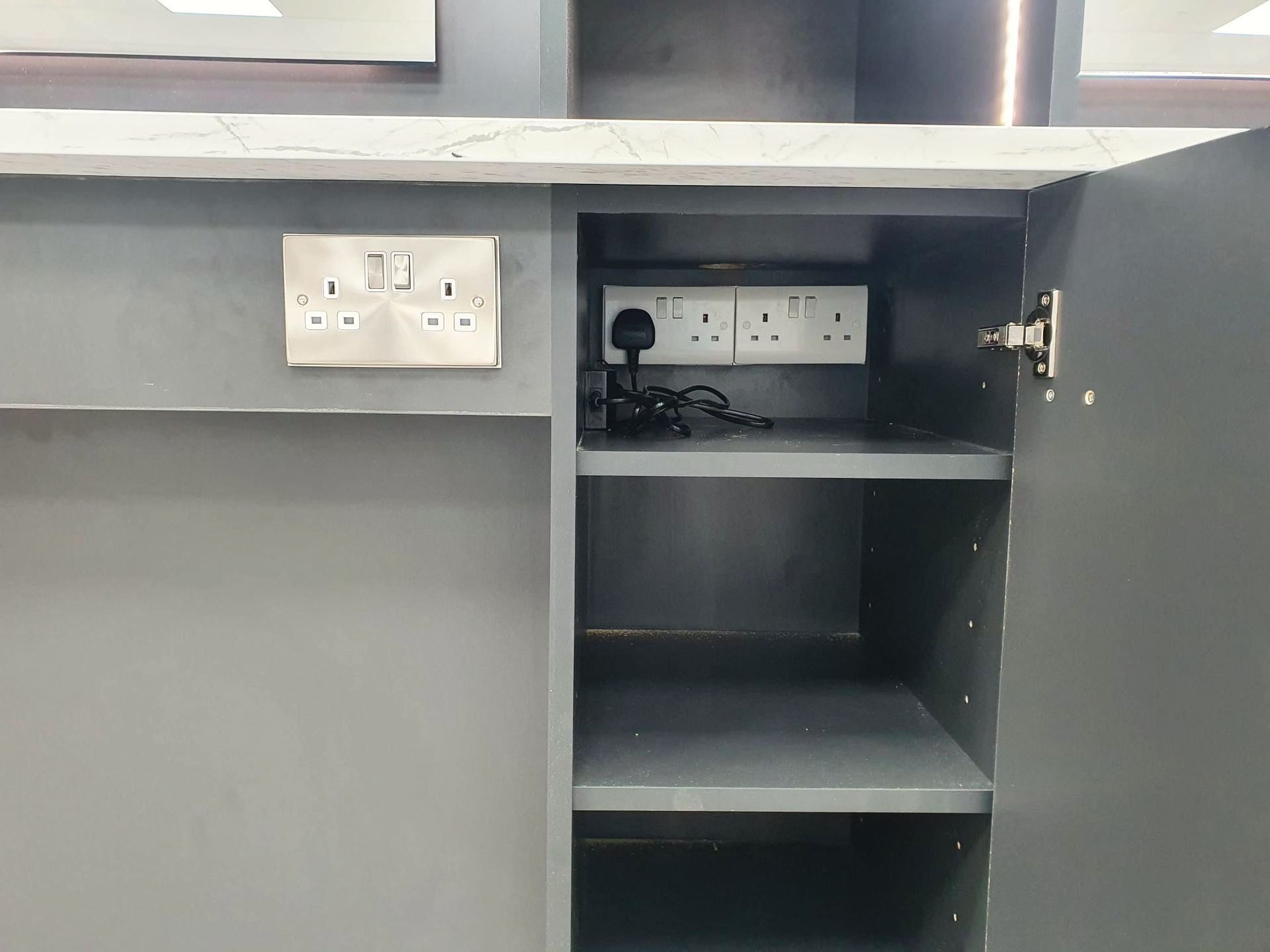 A gray cabinet with the door open and a few electrical outlets