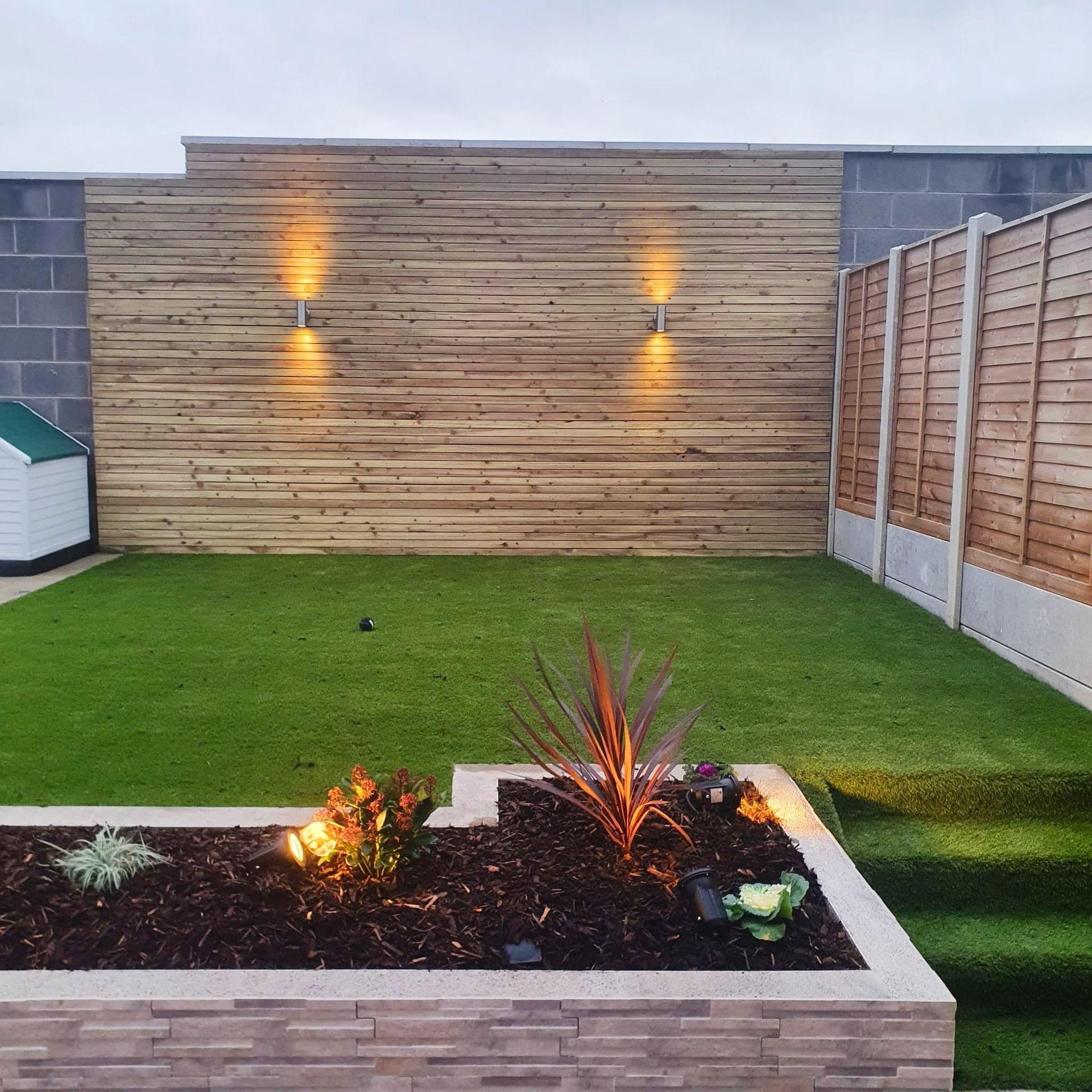 A garden with a wooden fence and a brick wall