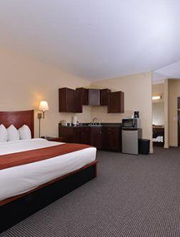Hotel room with king bed, bedside lamp, and small kitchenette area