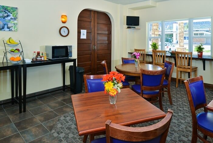 Bright café dining area with wooden tables, blue chairs, and arched double doors