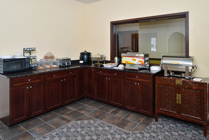 L-shaped kitchen buffet with dark wood cabinets, countertop appliances, and a tiled floor in a dining area