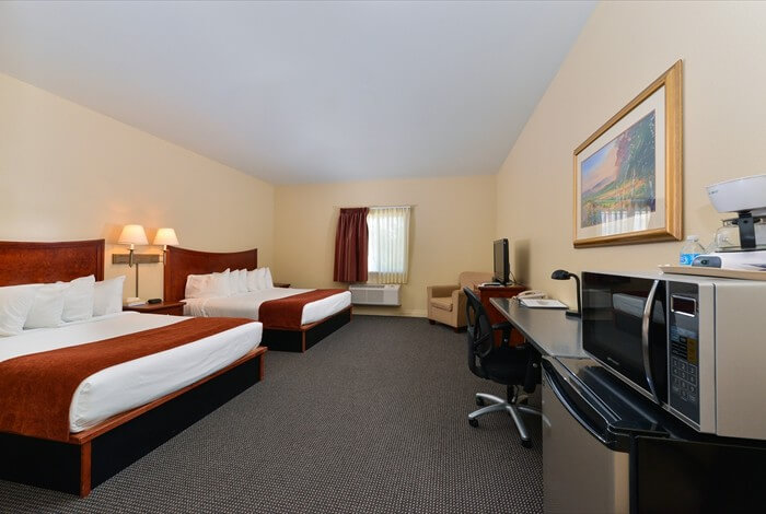 Hotel room with two beds, desk, TV, and microwave on a carpeted floor