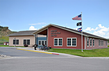 Modern red-and-tan building with flags flying and bikes parked outside on a sunny day