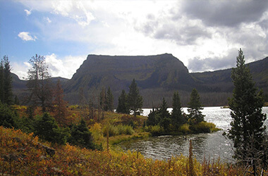 Mountain plateau above a river with autumn trees and cloudy sky