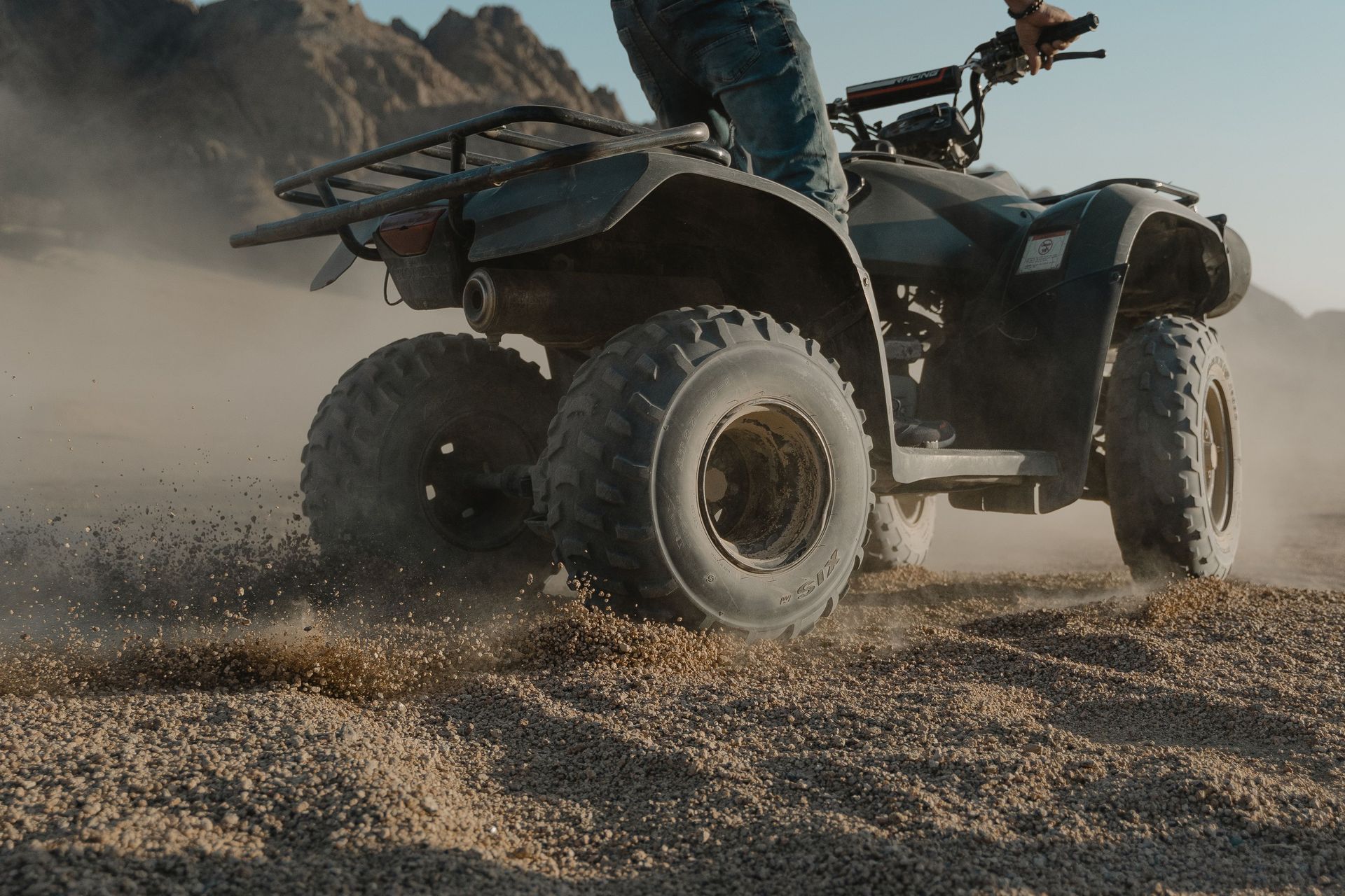 Off-road ATV kicking up dust on a rocky desert trail