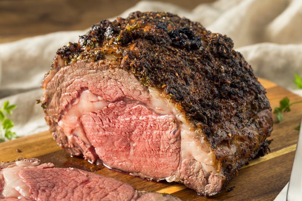 A large piece of meat is sitting on top of a wooden cutting board.