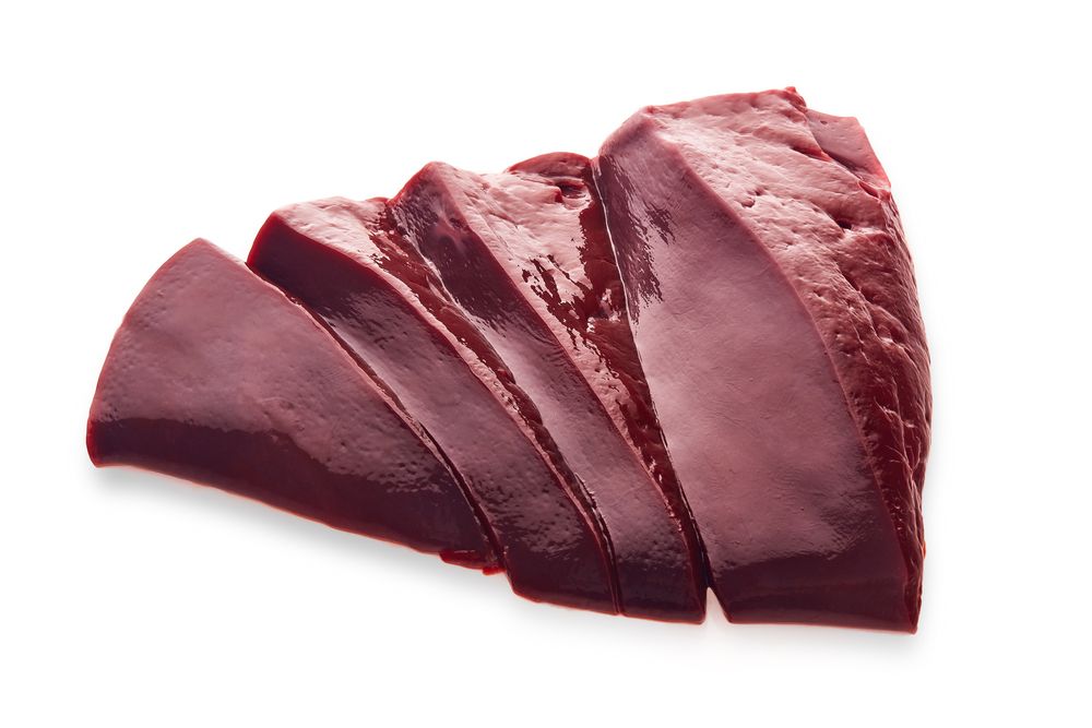 A piece of raw liver is sliced into pieces on a white background.