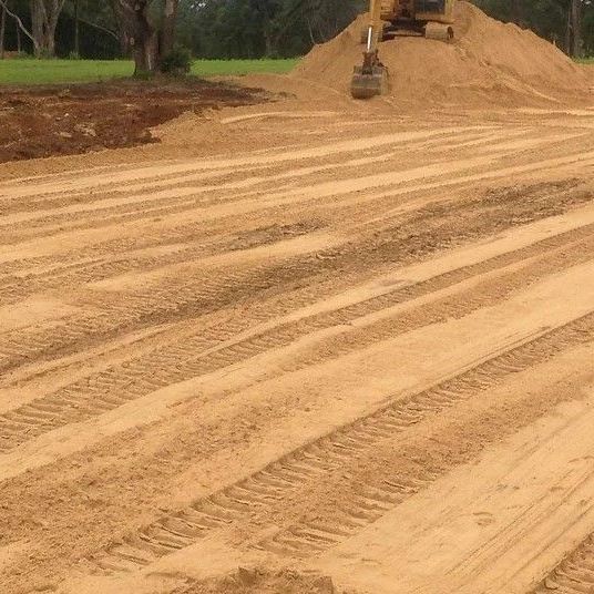 a bulldozer is moving dirt in a field with a pile of dirt in the background .