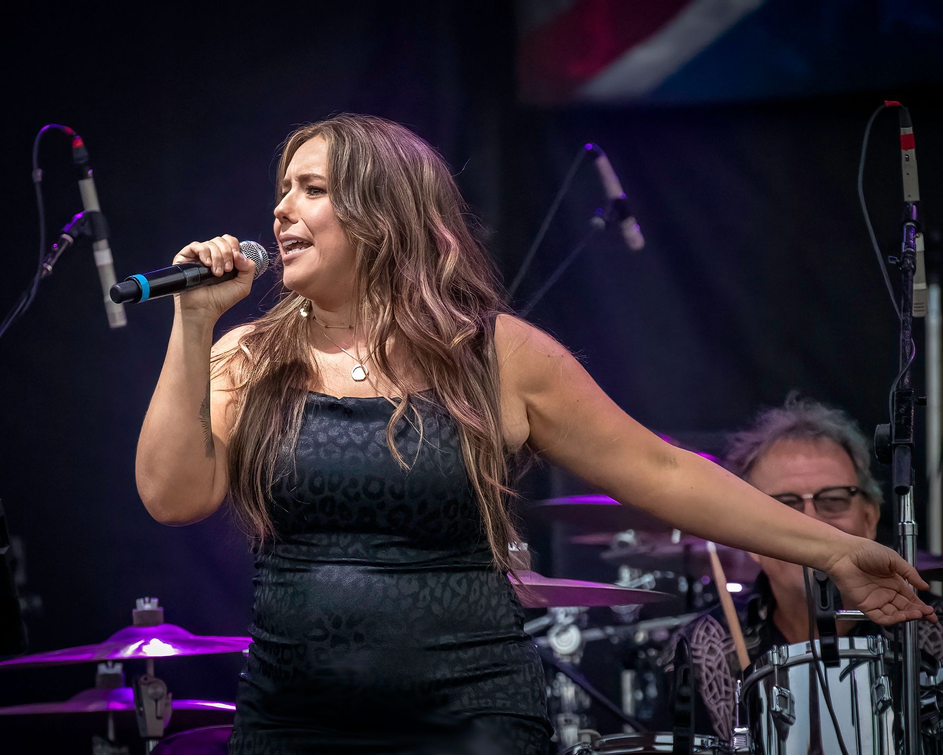 A woman is singing into a microphone on a stage.