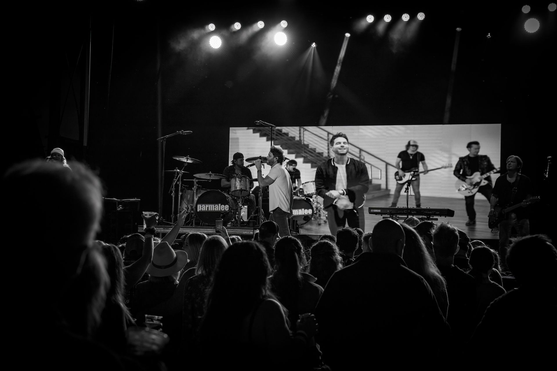 A black and white photo of a group of people playing instruments on a stage.