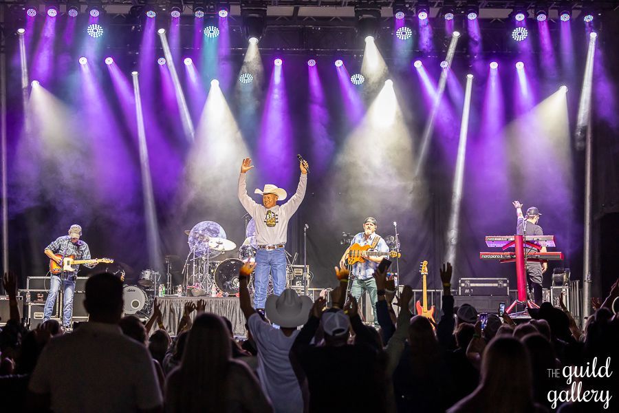A group of people are standing in front of a stage with purple lights.