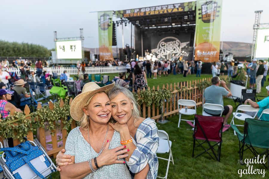 Two women are hugging each other in front of a crowd at a concert.