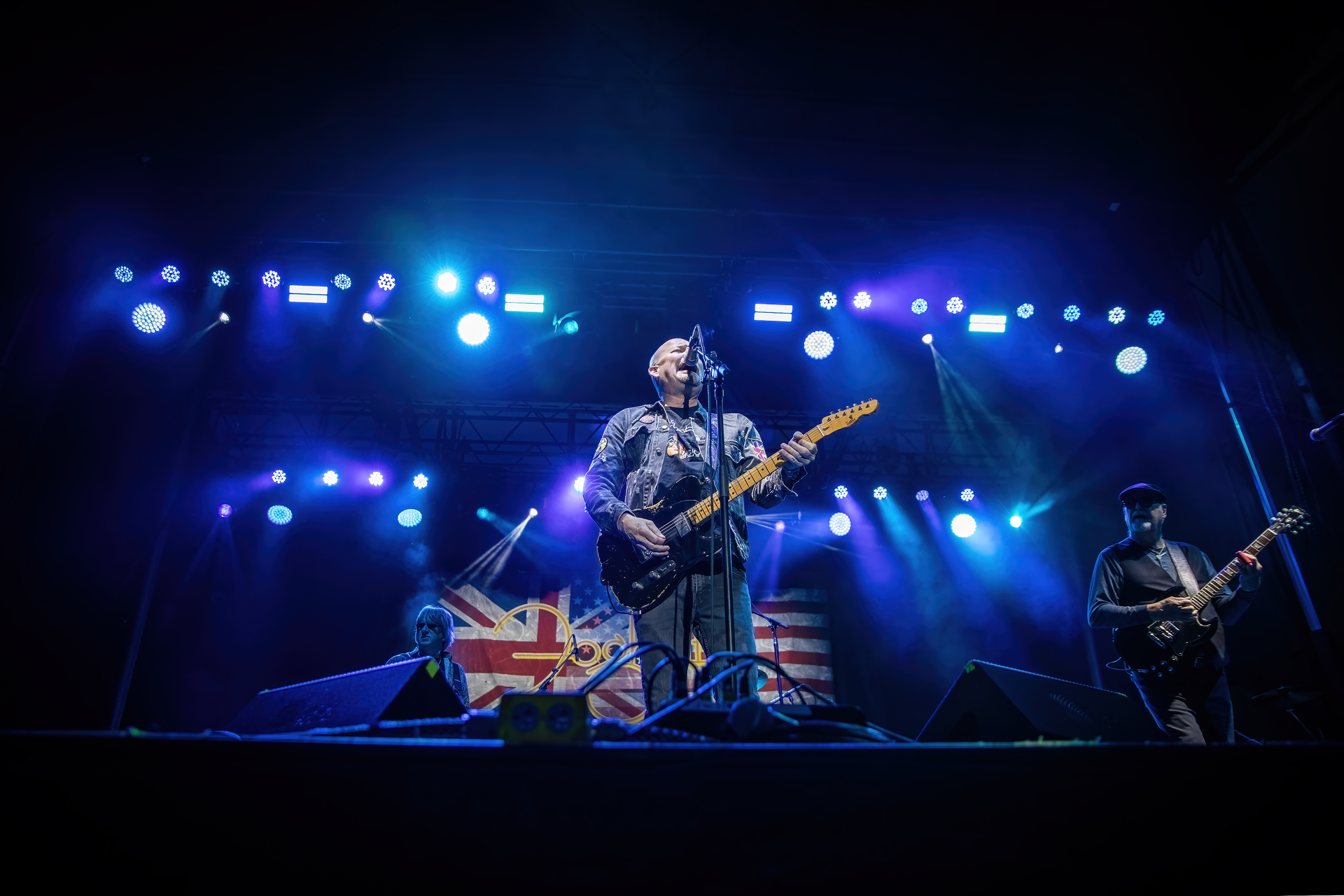 A man is playing a guitar and singing into a microphone on a stage.