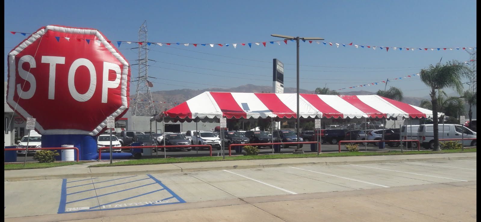 Large red STOP sign beside a red-and-white striped tent in a parking lot