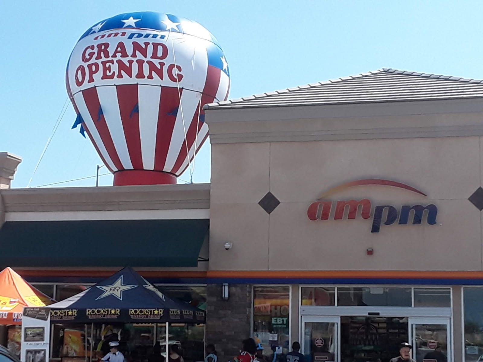 AmPm store exterior with a Grand Opening balloon in red, white, and blue