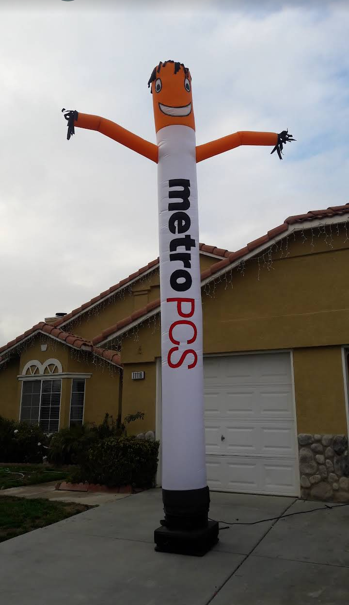 Orange inflatable Metropcs mascot waving outside a suburban house with garage