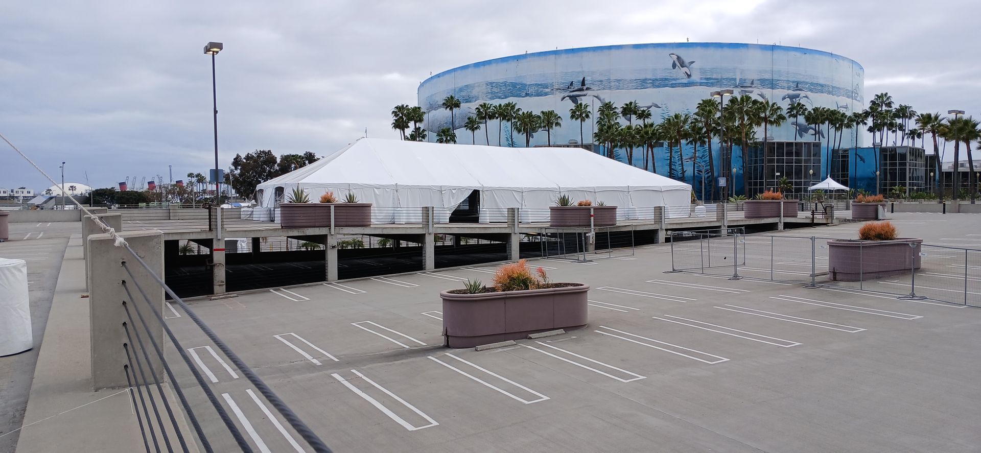Wide outdoor plaza with white tents, planters, and a large blue domed building in the background