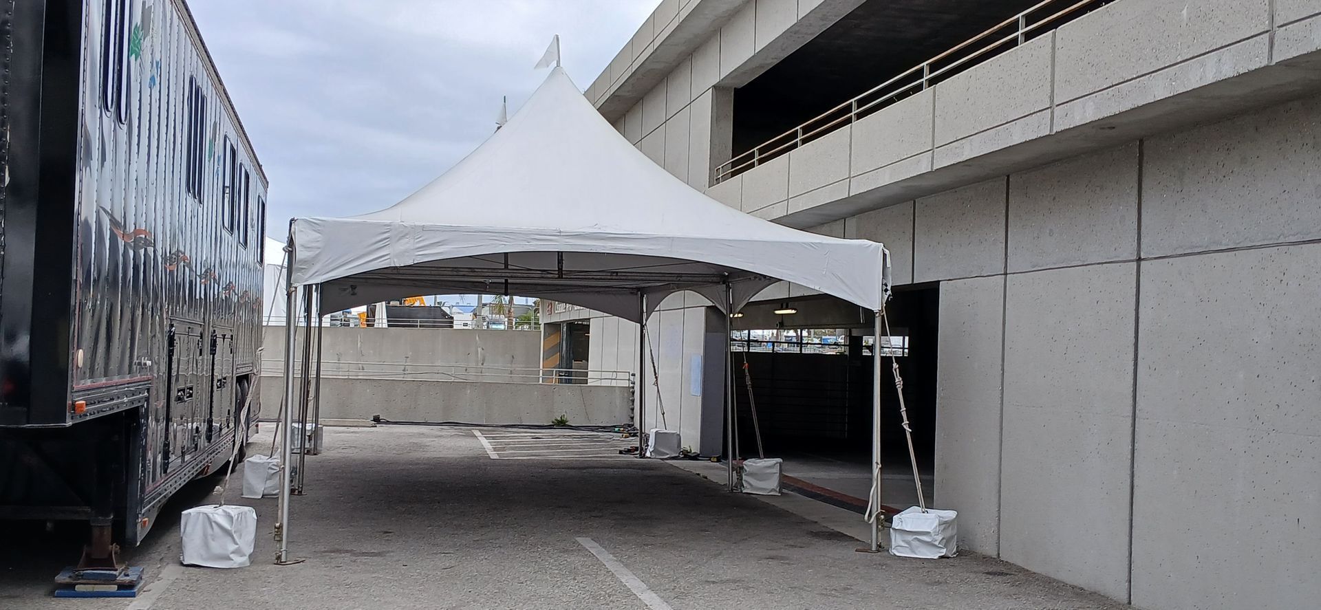 White canopy tent in a narrow outdoor passage between a truck and a building.