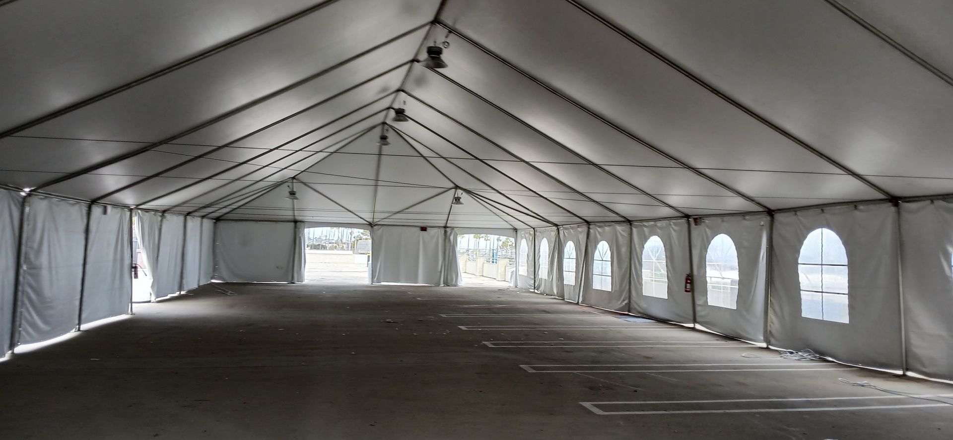 Empty white event tent interior with rows of windows and a peaked ceiling