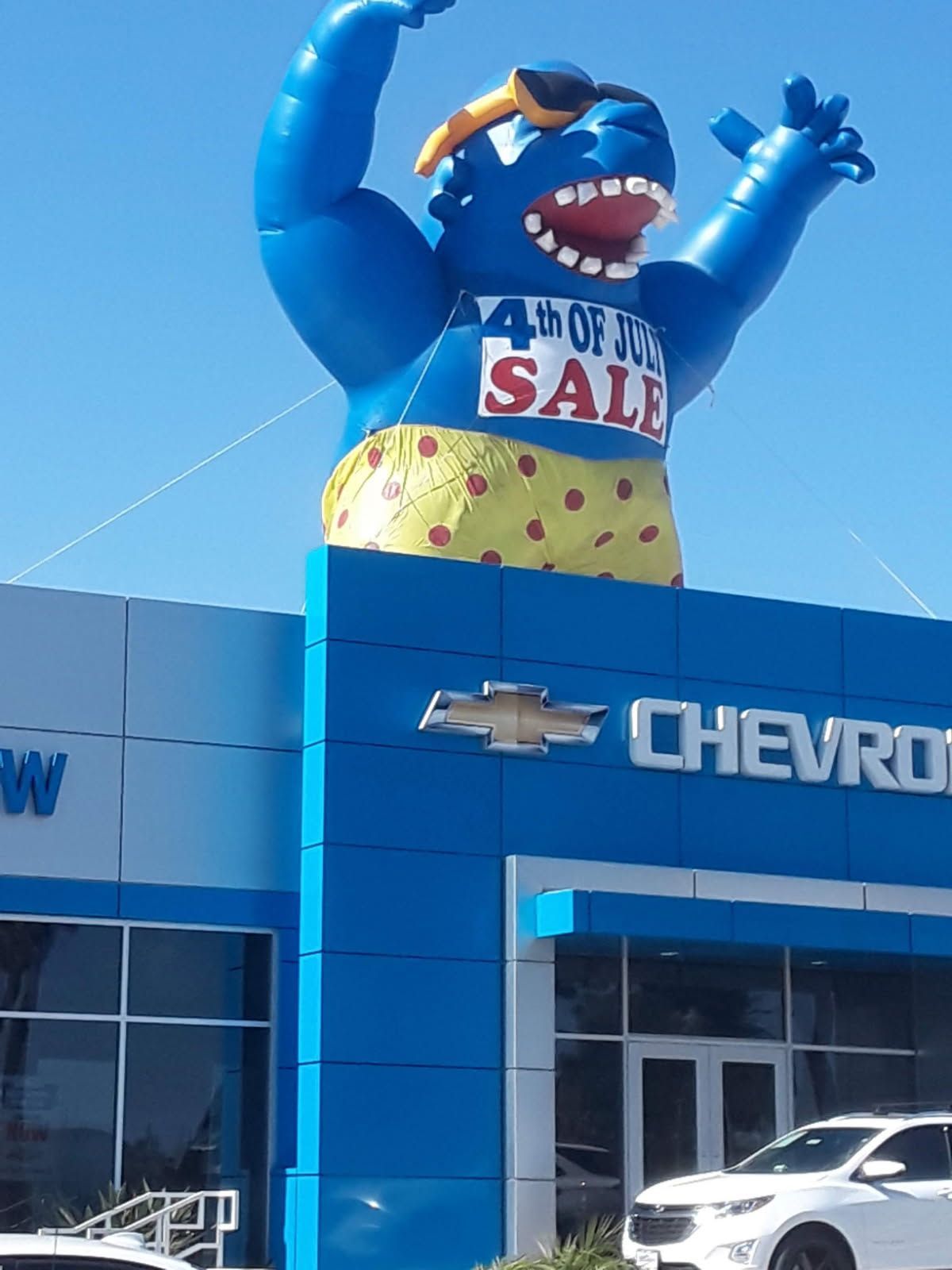 Blue inflatable monster advertising a sale outside a Chevrolet car dealership.