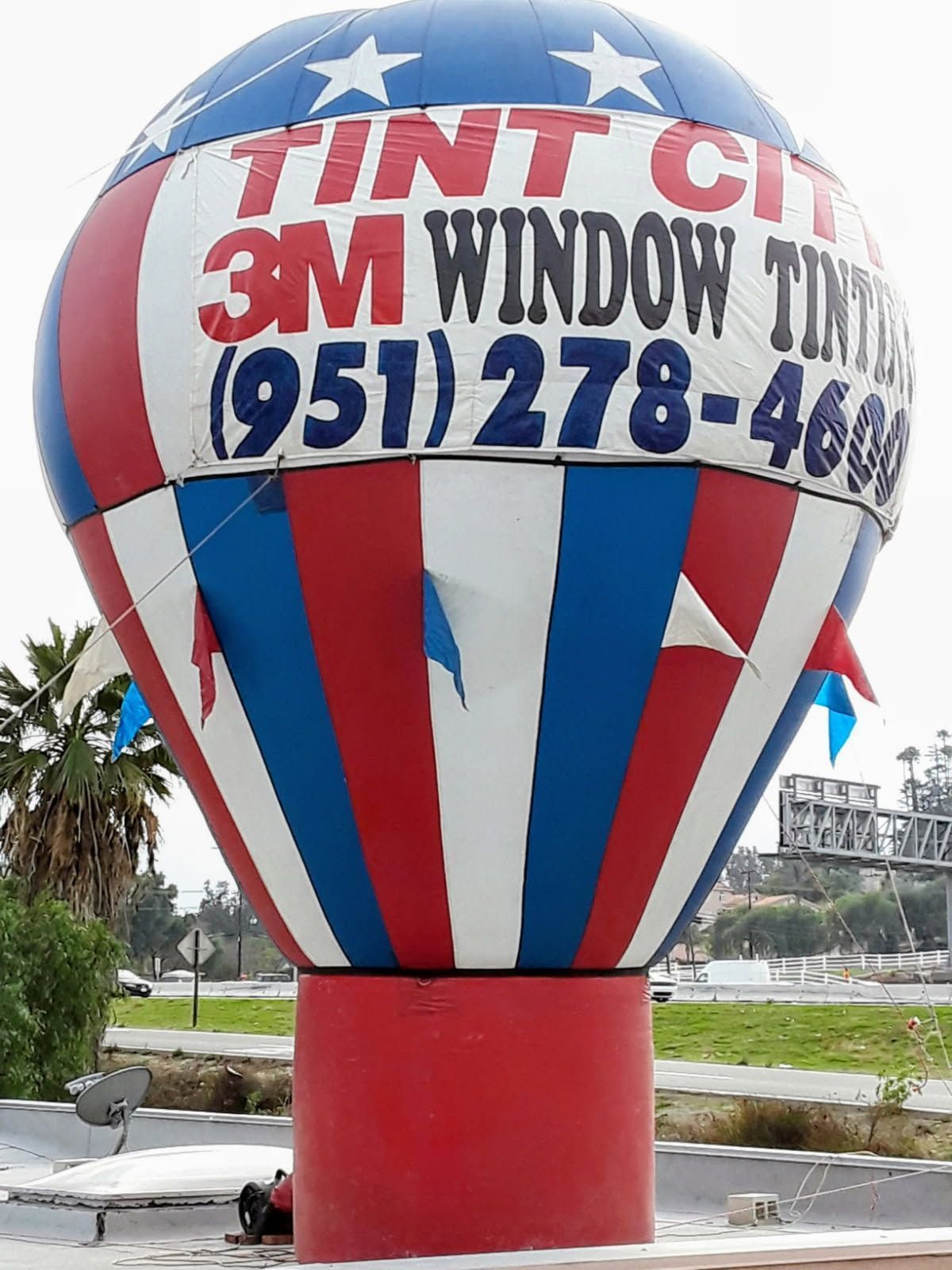 Red, white, and blue inflatable advertising balloon for Tint City 3M Window Tinting with phone number.