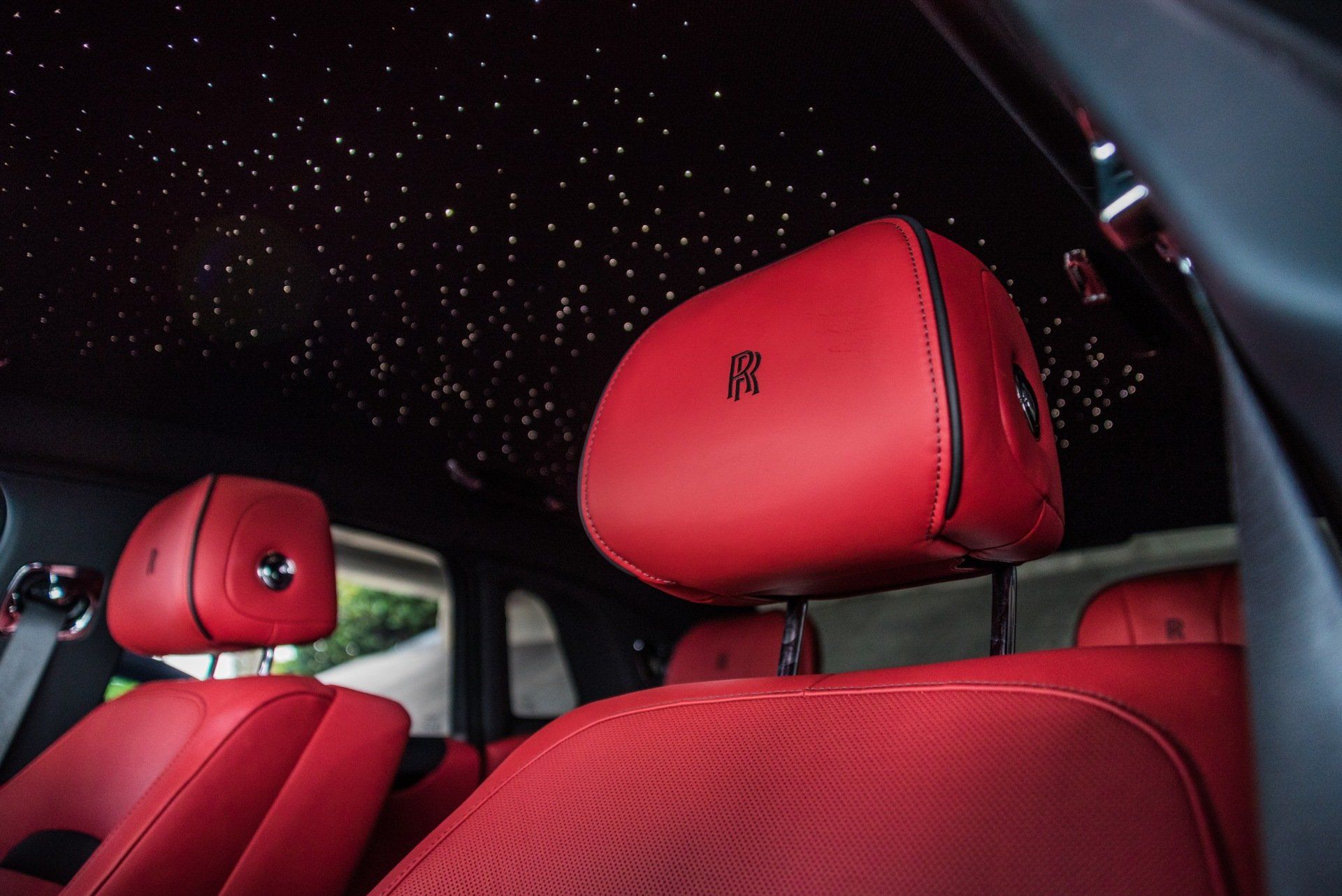 Red leather car seats with headrests, star-lit ceiling, and a Rolls-Royce logo.