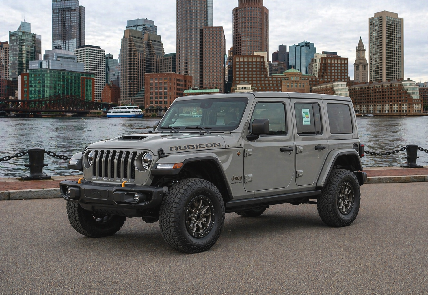Gray Jeep Wrangler on a paved road, with black wheels. Daytime, outdoor setting.