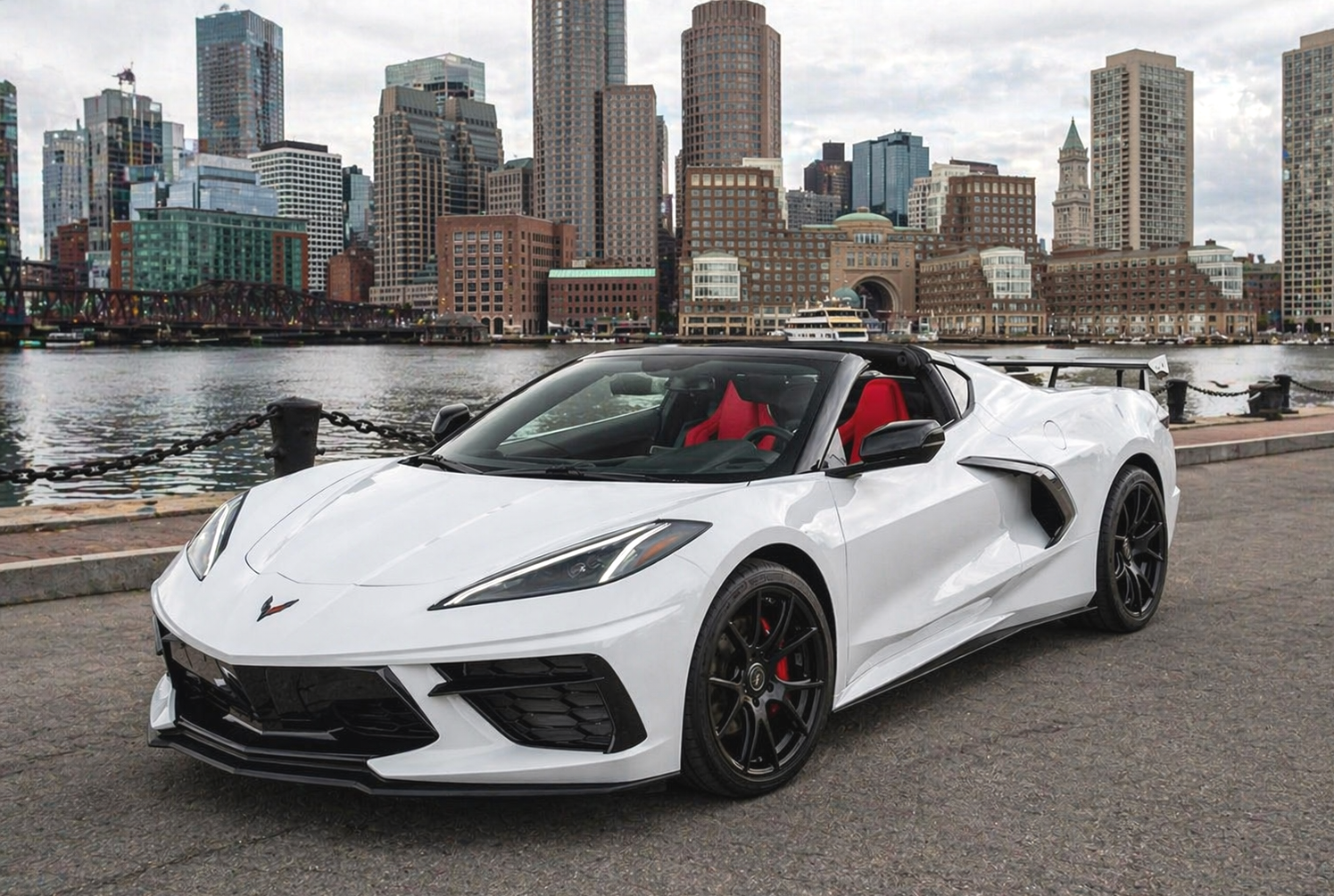 White Corvette convertible in a dark parking garage. Red interior, black wheels.