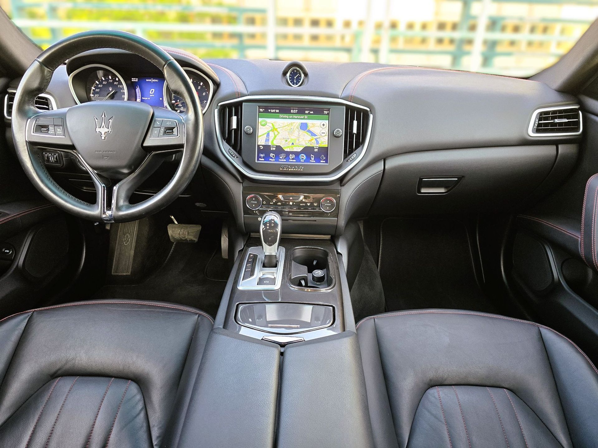 Luxury car interior with black leather seats, steering wheel, and center console with navigation screen.