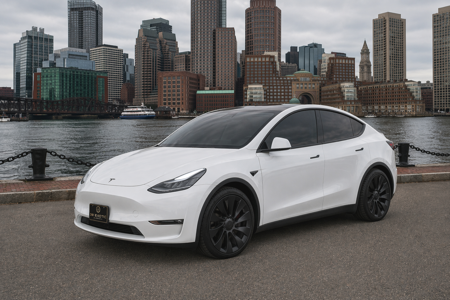 White Tesla Model Y parked outside a building with a black roof and dark wheels.