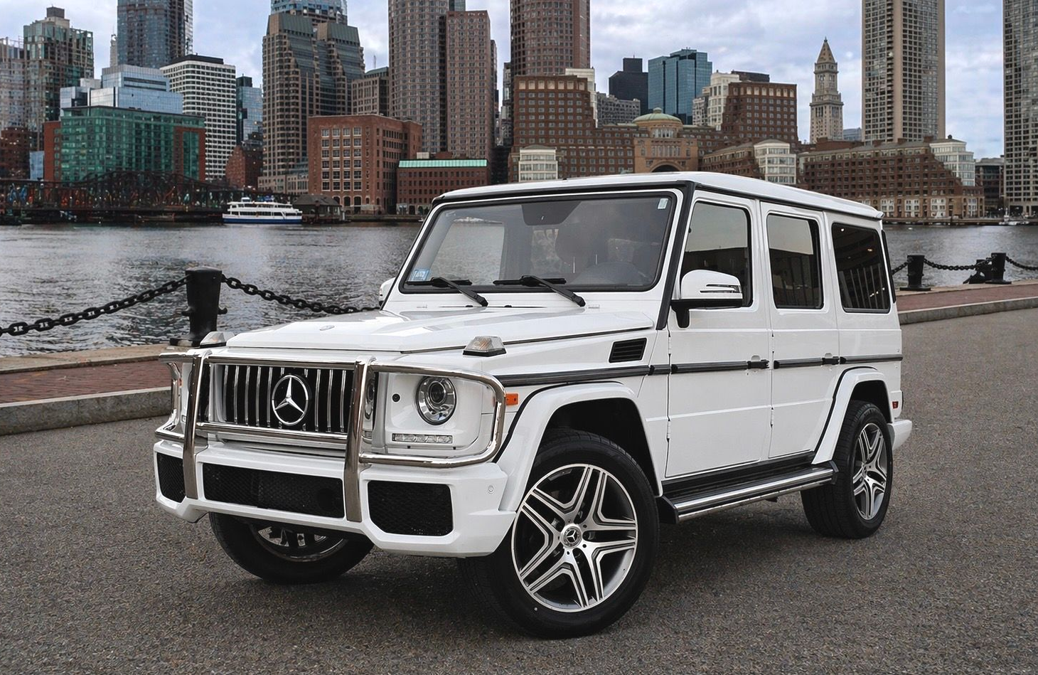 White Mercedes-Benz G-Wagon SUV parked on a rooftop with a city skyline in the background.
