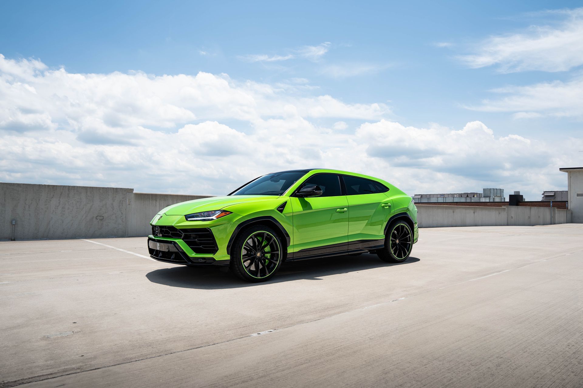 Green Lamborghini Urus SUV parked on a rooftop on a sunny day.