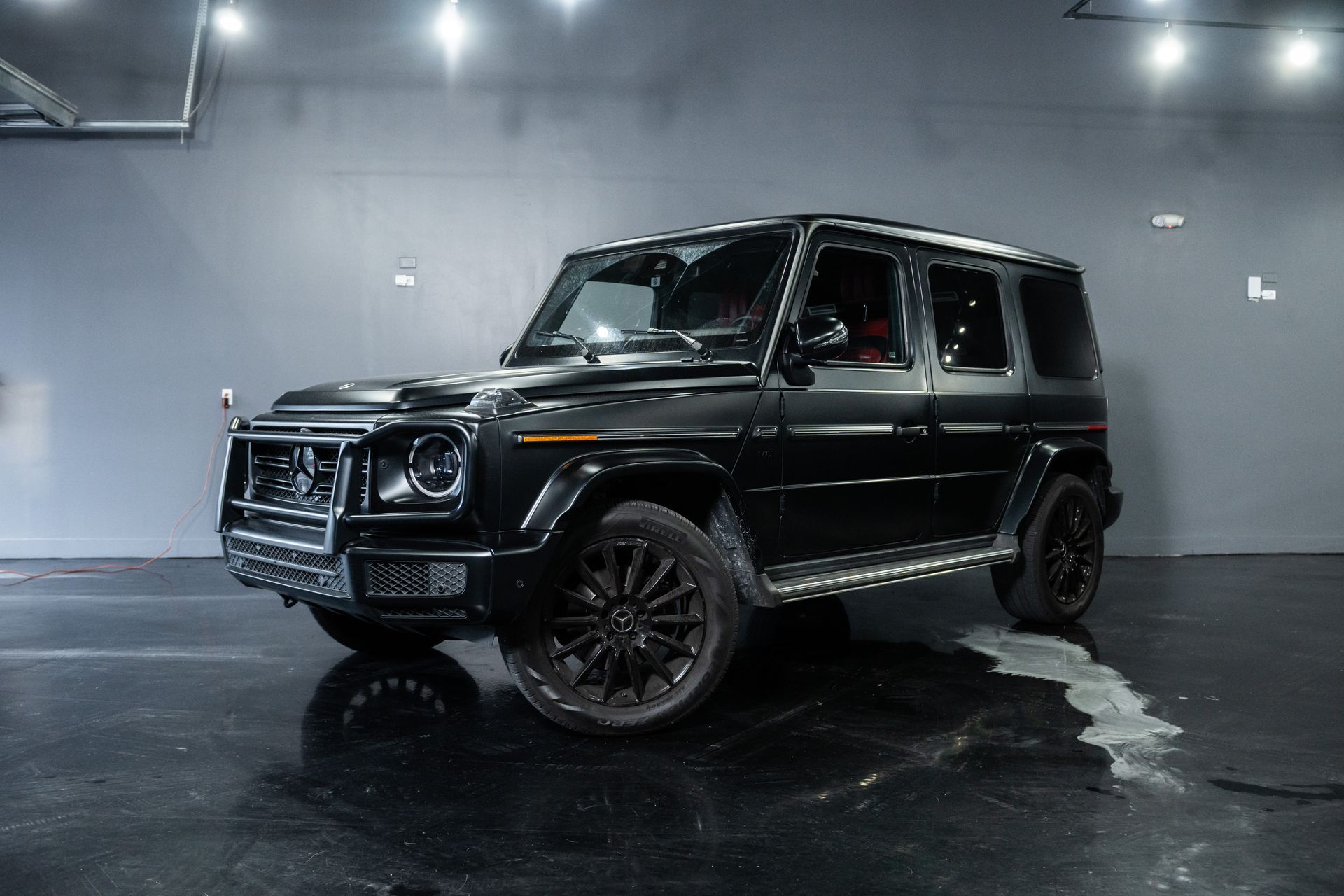 Black luxury SUV in a studio with wet reflective floor, front three-quarter view