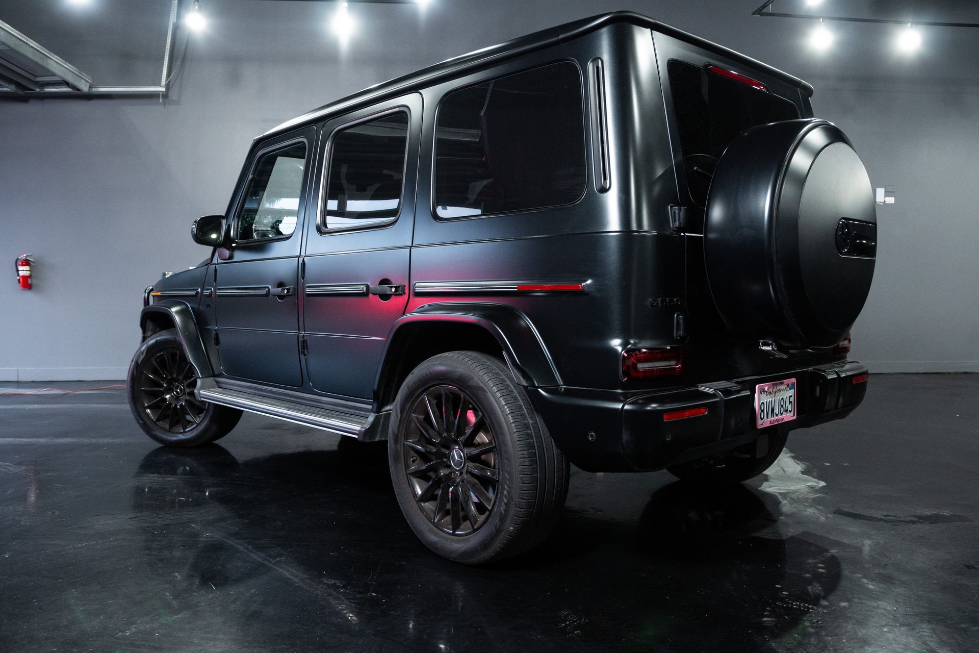Black Mercedes G-Class SUV in a showroom, rear three-quarter view with glossy paint and custom wheels