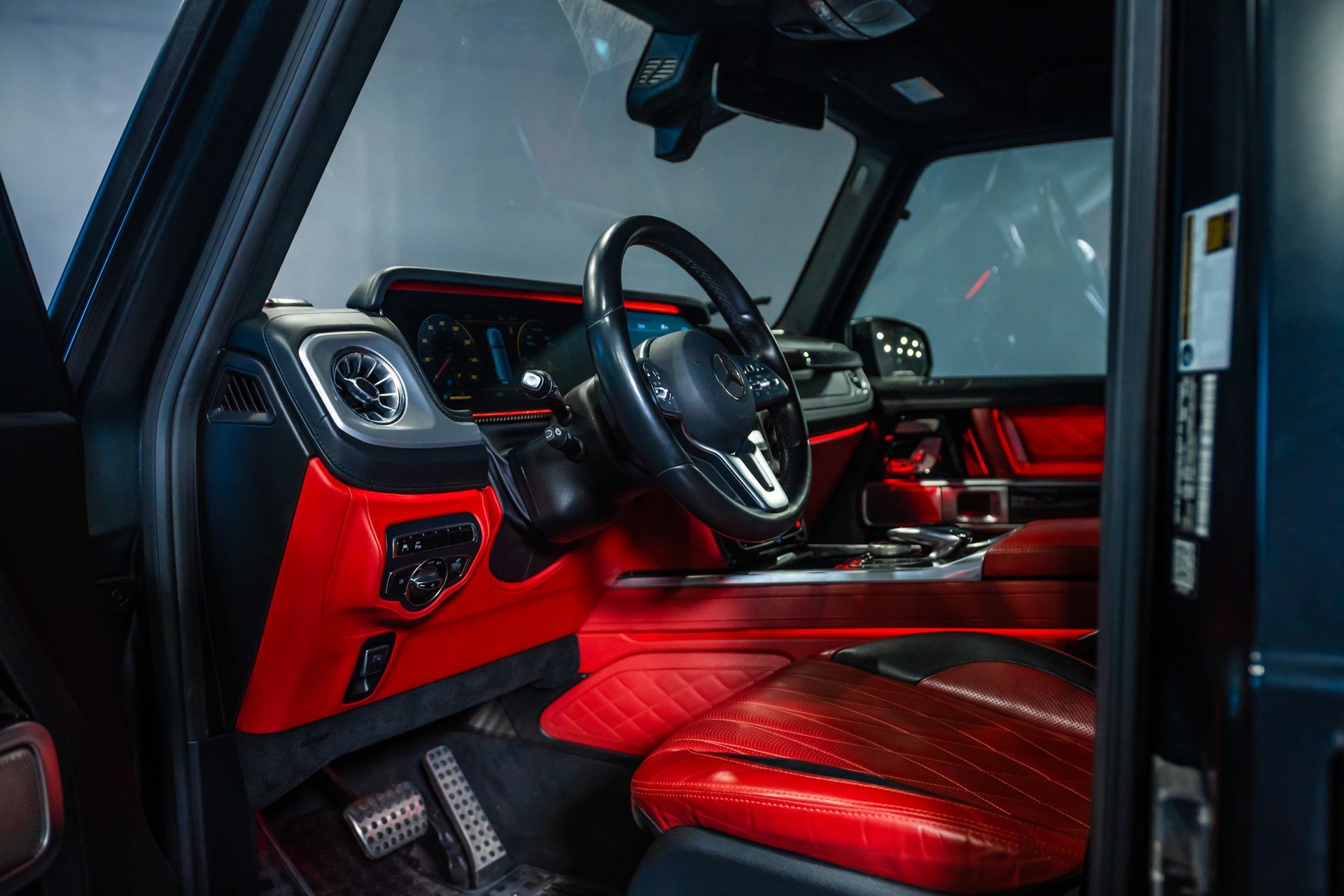 Red luxury car interior with black and red leather seats and dashboard, viewed from the open door