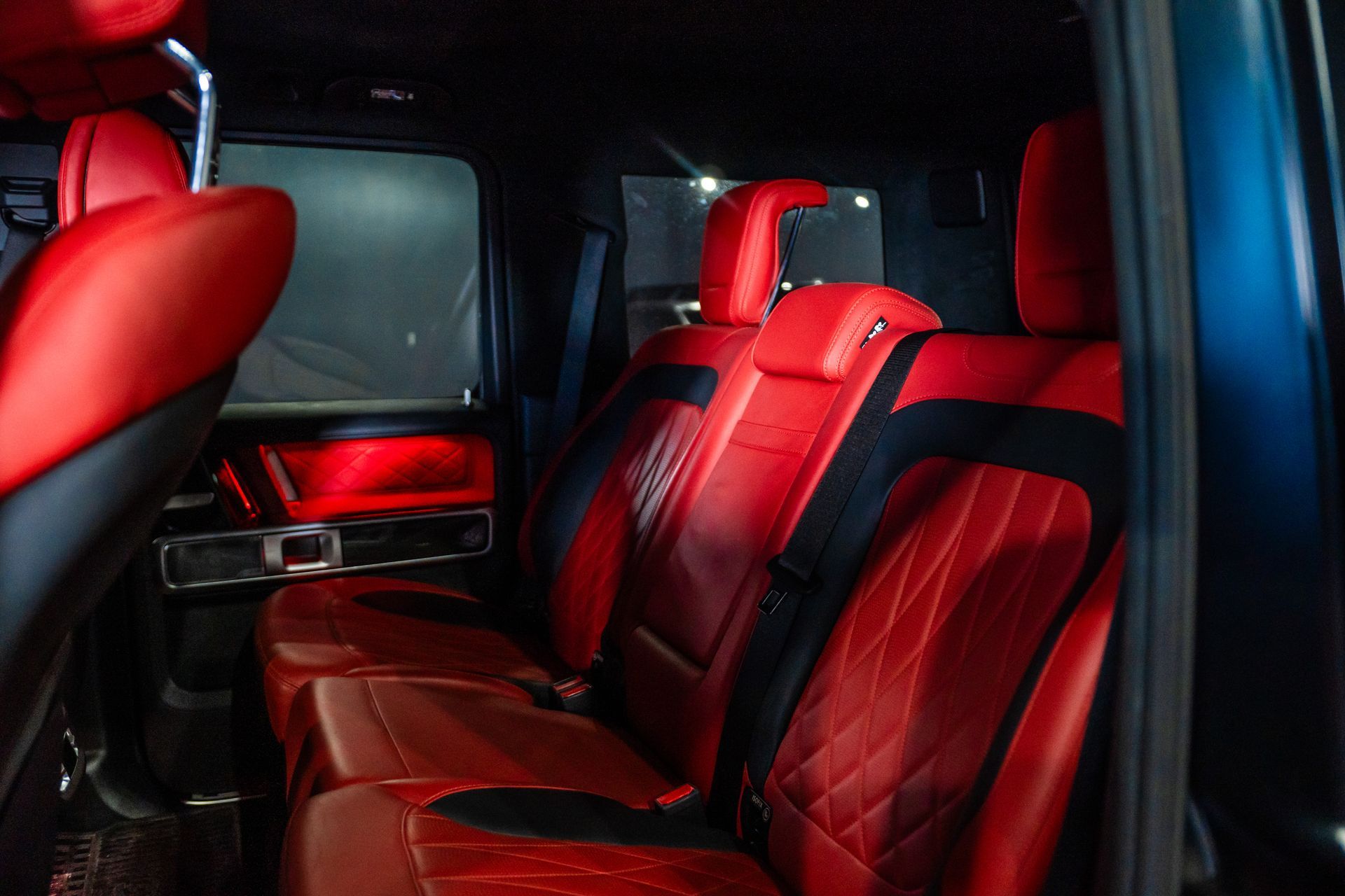 Red-and-black leather seats inside a car interior with dark windows
