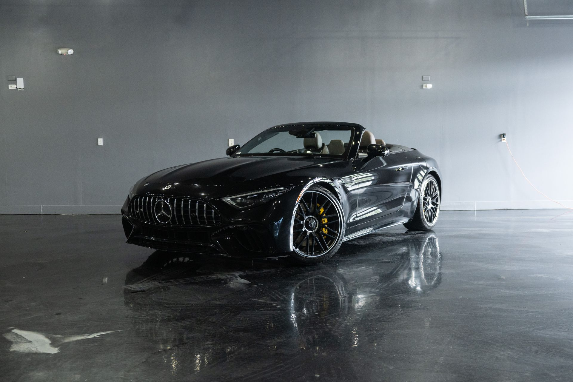 Black Mercedes-AMG GT Roadster on a reflective floor in a studio.