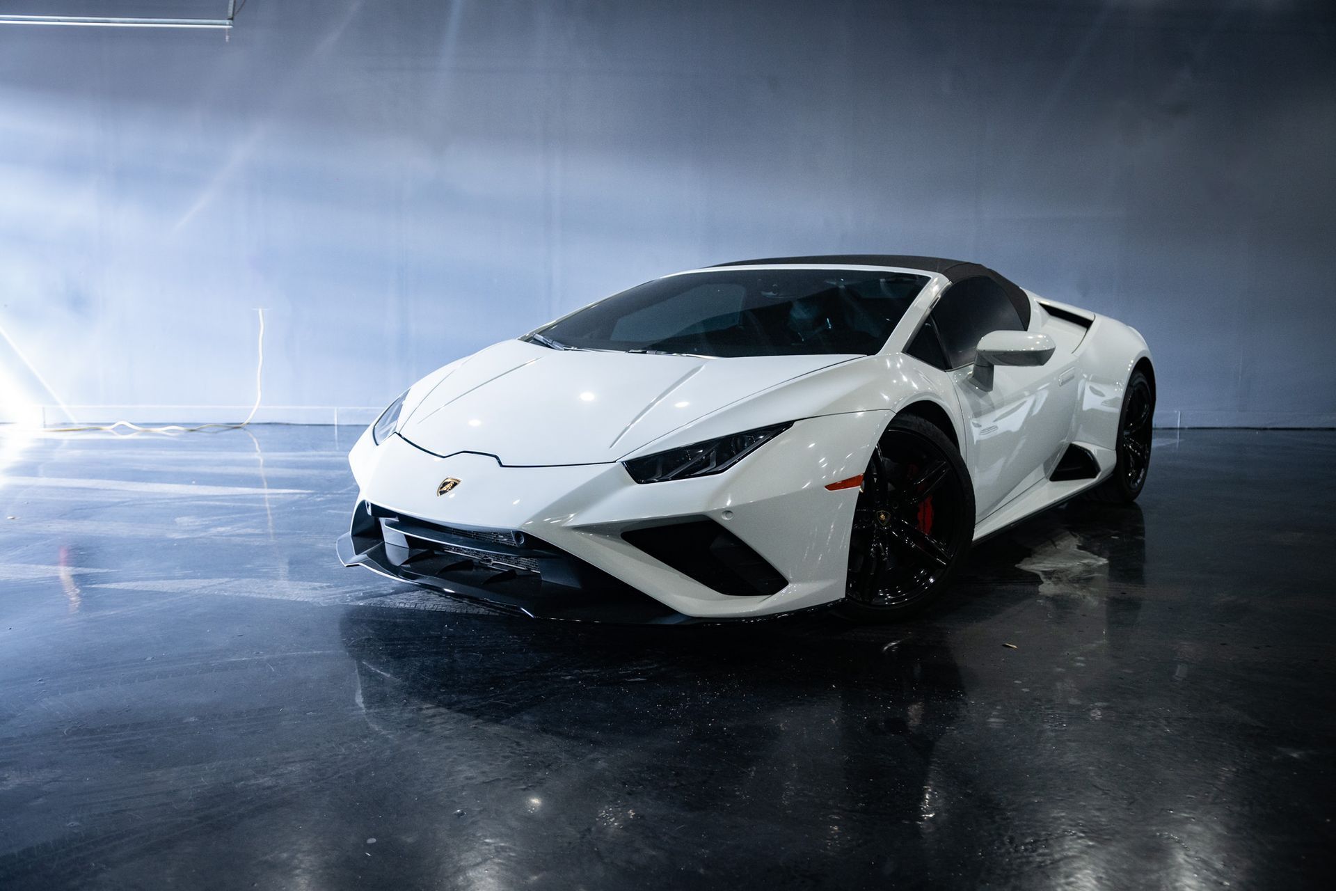 White Lamborghini Huracán Spyder parked on a wet, reflective surface.